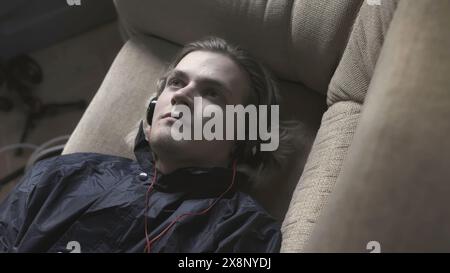 Young man is lying on couch and trying to fall asleep. Stock. Young man with anxiety is trying to fall asleep. Young man is lying on couch and Stock Photo