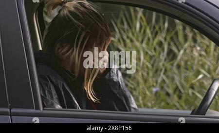 Young man is stressed in car. Stock. Young man is sitting in car on side of road and is stressed. Young man in car is stressed and has nervous Stock Photo