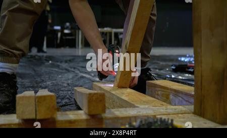 Carpenter working at workshop. Media. Worker using a screwdriver for assembling wooden construction. Stock Photo