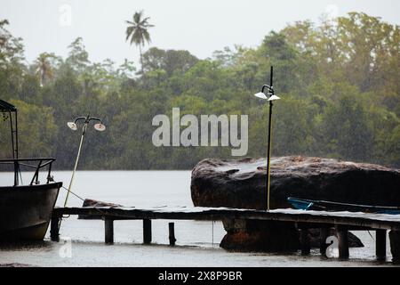 Falling raindrops of heavy rain against old pier in fishing village. Stock Photo