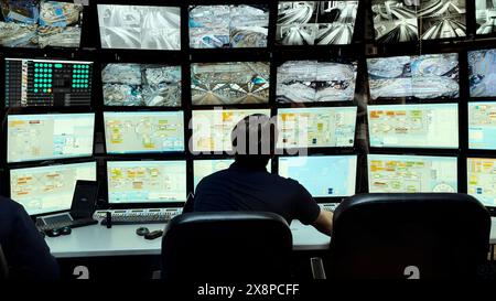 Security officer controls CCTV cameras in office, uses digital tablet and computers. Media. High tech software showing surveillance cameras, concept Stock Photo