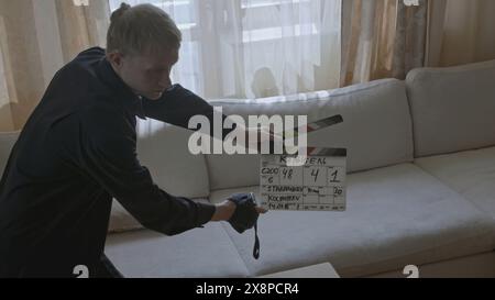 Man with clapperboard on set of movie. Stock. Man slaps clapperboard at beginning of movie shoot. Backstage with man and clapperboard before actors Stock Photo