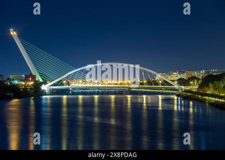 Night view of the Guadalquivir river in Seville with the Barqueta and Alamillo bridges, illuminated at dusk Stock Photo