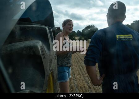 Adeline, farmer, talking with a colleague next to a tractor in a field at the Gaec du Bois farm in Cotes-d Armor, Brittany, France on July 21, 2022. A Stock Photo