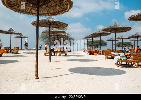 Sir Bani Yas, UAE - 5 January 2024: Visitors unwind on a pristine beach as the sun sets over the Arabian Gulf. Stock Photo