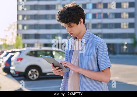 Young handsome male using digital tablet on city street Stock Photo