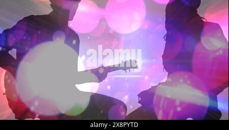 Image of colourful spots moving over silhouette of man and women playing guitar and drums Stock Photo