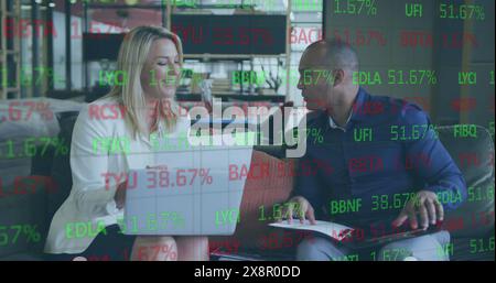 Two business colleagues are working on a laptop and discussing paperwork Stock Photo