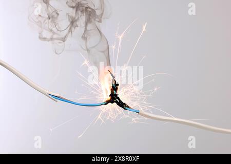 Sparking electrical wire on light background, closeup Stock Photo