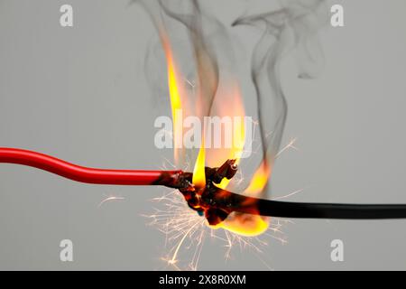 Electrical wire burning and sparking on light background, closeup Stock Photo