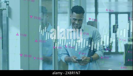 Image of multiple graphs and numbers moving over smiling biracial businessman using mobile phone Stock Photo