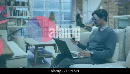 Image of infographic interface, biracial man sitting on couch with laptop and talking on phone Stock Photo