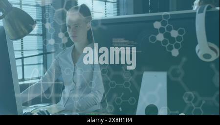 Image of computer language and molecule structures over caucasian woman working on desktop Stock Photo