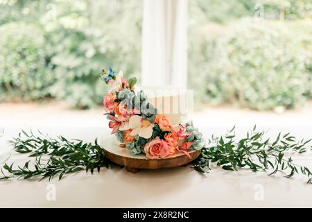 Elegant two-tiered wedding cake with floral decorations and greenery Stock Photo