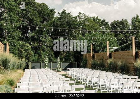 Outdoor wedding aisle with white chairs under lights Stock Photo