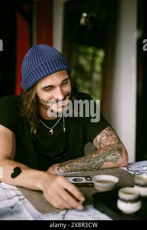 Young smiling man with long hair wearing a blue hat. Stock Photo
