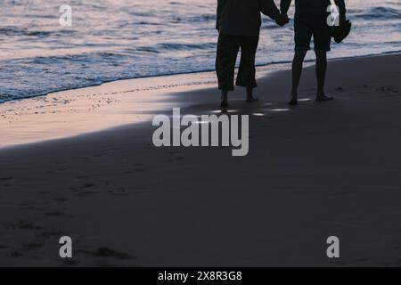 Couple walks at sunset on a Corfu beach, Greece Stock Photo