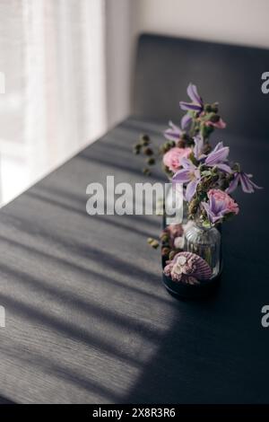 Flower arrangement in glass vases on a dark table with soft light Stock Photo