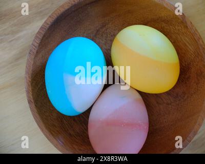Colorful DIY Decorated Easter Eggs on Wooden Plate Stock Photo