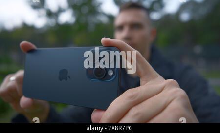 UK, London - September 15, 2023: Man takes pictures on new iPhone. Action. Apple's logo on new iPhone 15 pro. Shooting on new iPhone 15 pro in nature Stock Photo