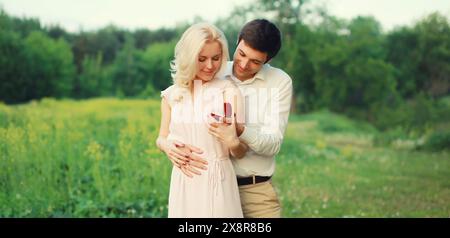 Wedding concept, happy lovely young couple, man proposing a ring to his beloved woman outdoors in summer park Stock Photo