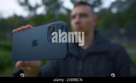 UK, London - September 15, 2023: Man takes pictures on new iPhone. Action. Apple's logo on new iPhone 15 pro. Shooting on new iPhone 15 pro in nature Stock Photo