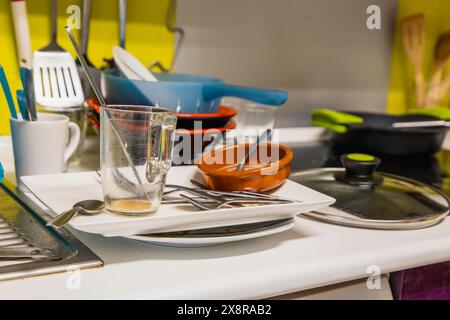 A messy kitchen counter with dirty dishes and glasses after dinner. Scene is chaotic and disorganized Stock Photo