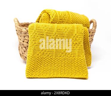 Yellow wool knitted blanket in diamonds pattern in basket on white background Stock Photo