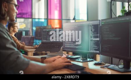 Professional Male Data Scientist Writing Code on Desktop Computer in Stylish Coworking Office Space. Caucasian Man Using Software to Analyze Information From Internet and Improve Performance. Stock Photo