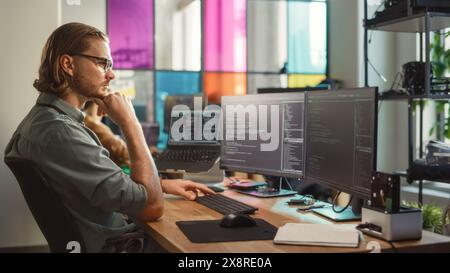 Professional Male Data Scientist Writing Code on Desktop Computer in Stylish Coworking Office Space. Caucasian Man Using Software to Analyze Information From Internet and Improve Performance. Stock Photo