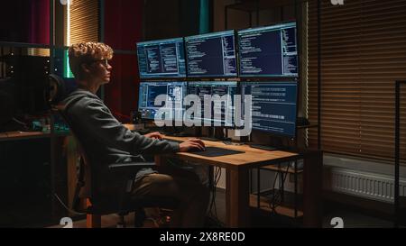 Young Cyber Security Expert Writing Code on Desktop PC With Professional Six Monitors Setup in the Dark Office. Smart Caucasian Man Monitors Digital Protection System For an Intelligence IT Department Stock Photo