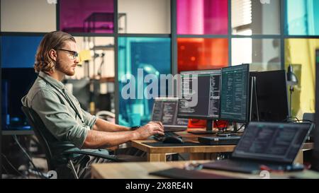 Caucasian Man Writes Code on Desktop Computer With Professional Multiple Monitors Setup in Modern Office. Male Data Scientist Using Software to Collect and Analyze Information From Opened Sources. Stock Photo