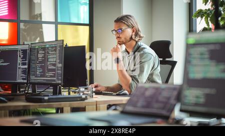 Focused Caucasian Man Coding On Desktop Computer in Stylish Office Space. Male Software Engineer Developing Innovative Application For Business Customers in Technological Start-up Company. Stock Photo