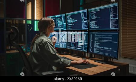 Cyber Security Agency: Female Programmer Coding on Desktop Computer With Six Displays in Dark Office. Caucasian Woman Monitors Data Protection System, Monitoring Information on SAAS Servers. Stock Photo