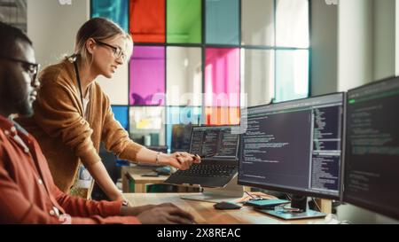 Black Programmer Shows Code On Desktop Computer to Female Start-Up Founder in Creative Office Space. African Man And Caucasian Woman Discussing New Software Features For Mobile Application. Stock Photo