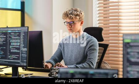 Male Software Engineer Coding On Desktop Computer in Creative Office Space. Young Caucasian Man Applying His Programming Skills in Innovative Technological Startup. Junior Developer Working. Stock Photo