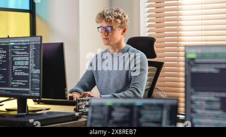 Male Software Engineer Coding On Desktop Computer in Creative Office Space. Young Caucasian Man Applying His Programming Skills in Innovative Technological Startup. Junior Developer Working. Stock Photo