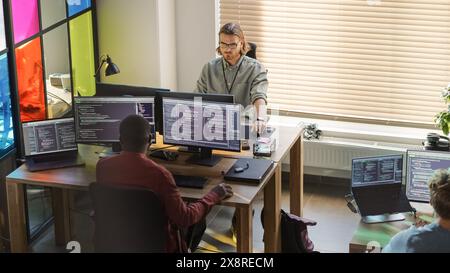 Diverse Colleagues Writing Code on Desktop Computers With Professional Multiple Monitors Setup. Software Development Team Working on Software as a Service Platform For Business Clients. Stock Photo