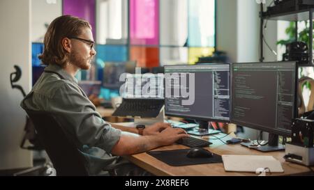 Male Programmer Using Desktop Computer And Laptop To Write Code In Creative Office. Caucasian Man Using Multiple Displays Set Up. Developing Software As A Service Platform For Innovative Start-Up. Stock Photo
