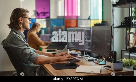 Professional Male Developer Writing Code On Desktop Computer With Two Displays and a Laptop in Creative Office. Caucasian Man Programming Artificial Intelligence Software For Big Tech Company. Stock Photo