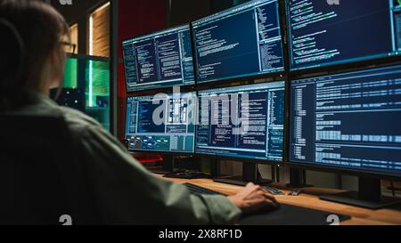 Female Cyber Security Student Coding on Desktop PC With Six Monitors Setup in Dark Office. Caucasian Woman Finishes Internship for Big IT Company. Monitoring Protection System, SAAS Server Data. Stock Photo