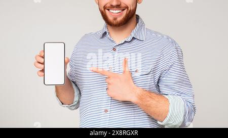 Smiling millennial man holding latest slim cellphone, cropped Stock Photo