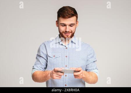 Young guy playing games on his phone and having fun Stock Photo