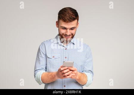 Young man absorbedly text messaging on his cellphone Stock Photo