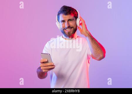 Man Wearing Headphones and Holding Cell Phone Stock Photo