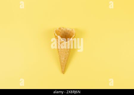 Top view of ice cream waffle cone on yellow background. Summer wallpaper, flat lay, copy space. Stock Photo