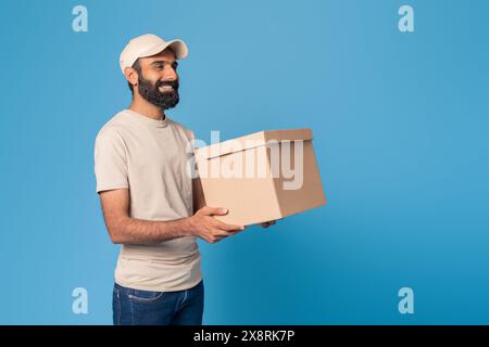 Bearded Man Holding a Brown Box Against Blue Background Stock Photo