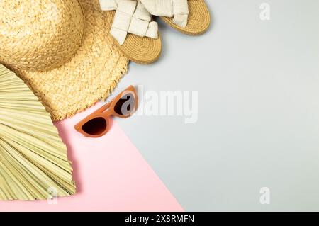 Top view of straw hat, slippers, sunglass and dried palm leaf on colorful background. Summer fashion, vacation and beach wallpaper. Copy space. Stock Photo