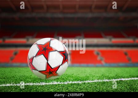 A soccer ball with orange stars on a grass, with an orange stadium stand in the background, perfect for sports-themed designs and concepts. Stock Photo