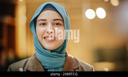 Portrait of Muslim Successful Businesswoman Wearing Hijab Looking at Camera and Smiling. Face Close Up of a Successful Empowered and Confident Arab Woman. Bokeh Blurred Background Stock Photo